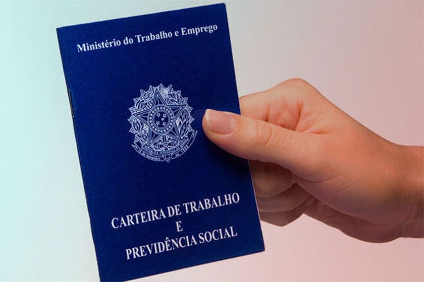 Seguro-Desemprego: uma pessoa branca segura a Carteira de Trabalho e Previdência Social.